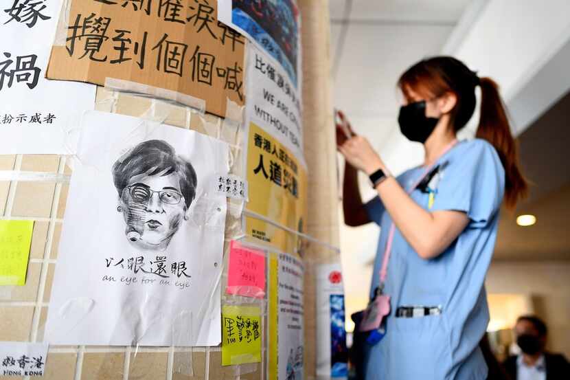 A nurse sticks posters next to a caricature of  Chief Executive Carrie Lam during a...