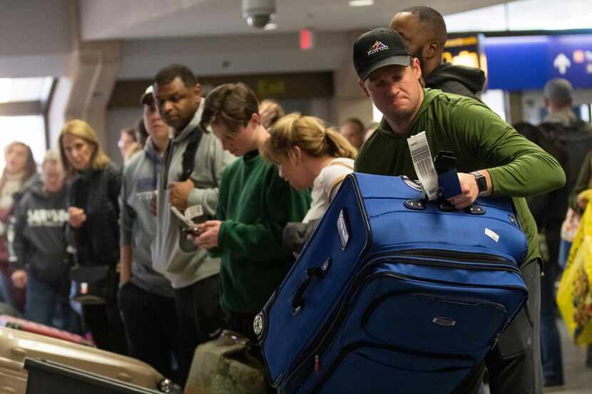 Matt Murphy (right) picks up his luggage at Terminal C during the busiest day ever at DFW...