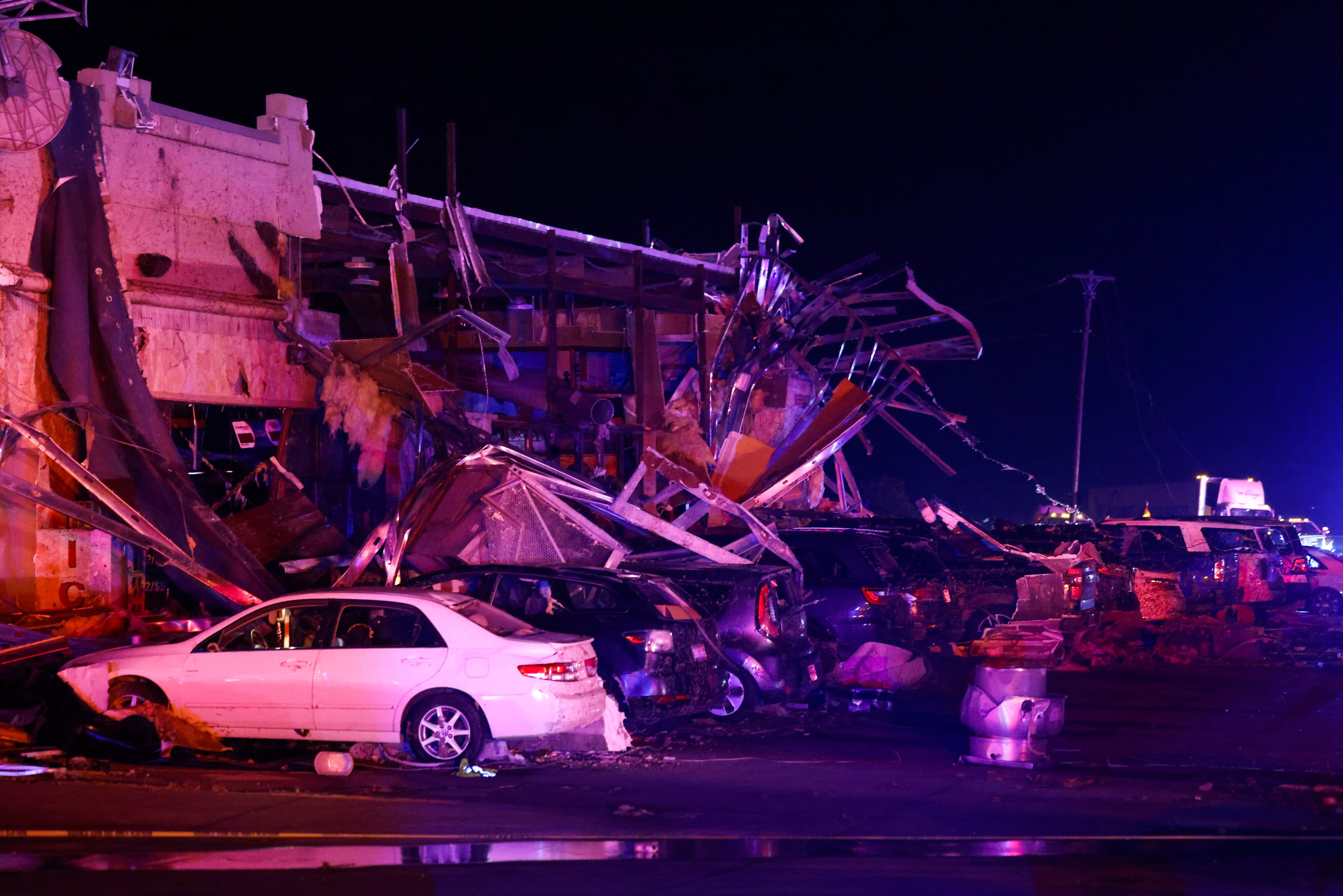 Several cars are seen heavily damaged outside the remains of a Shell gas station after a...