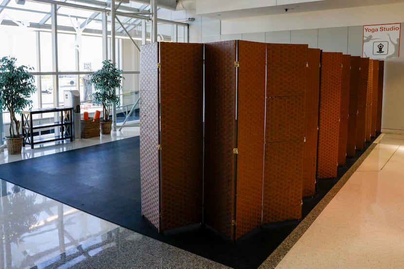 A privacy divider marks the edge of a yoga studio mat in Terminal E, Tuesday, Oct. 31, 2023,...