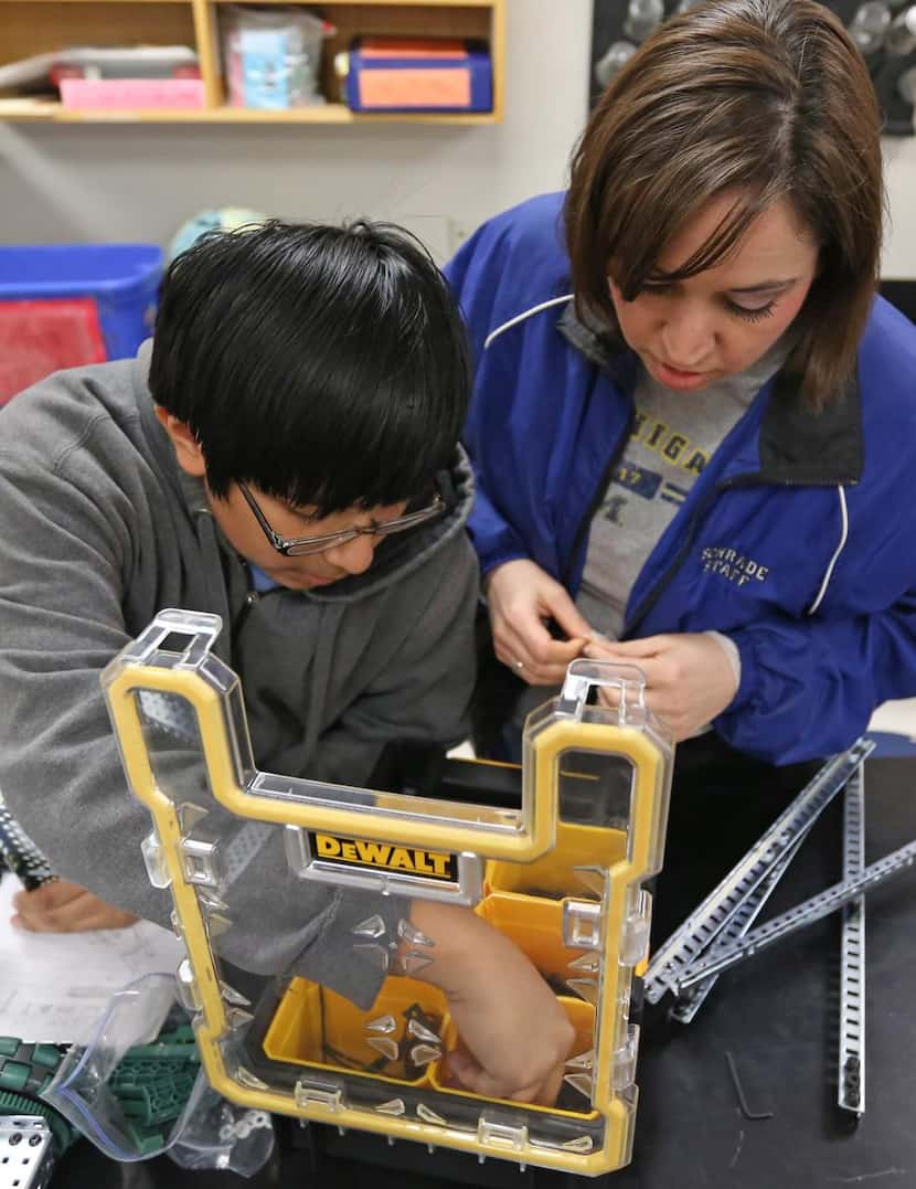 
Eighth-grader Mauricio Roldan works on his robot with guidance from his teacher, Farideh...