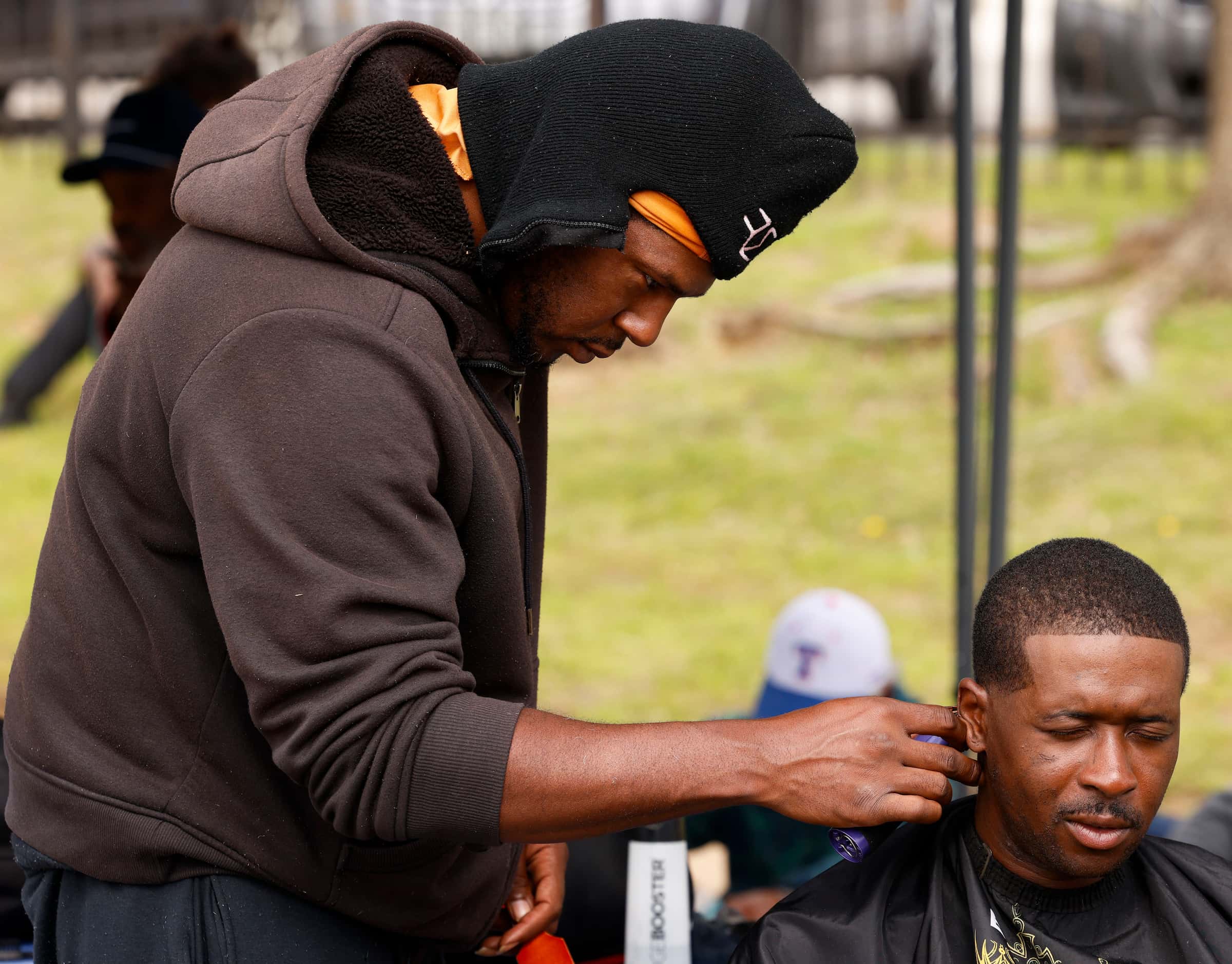 Barber King Jaymes Bell (left) gives haircut to an individual during first city-sanctioned...
