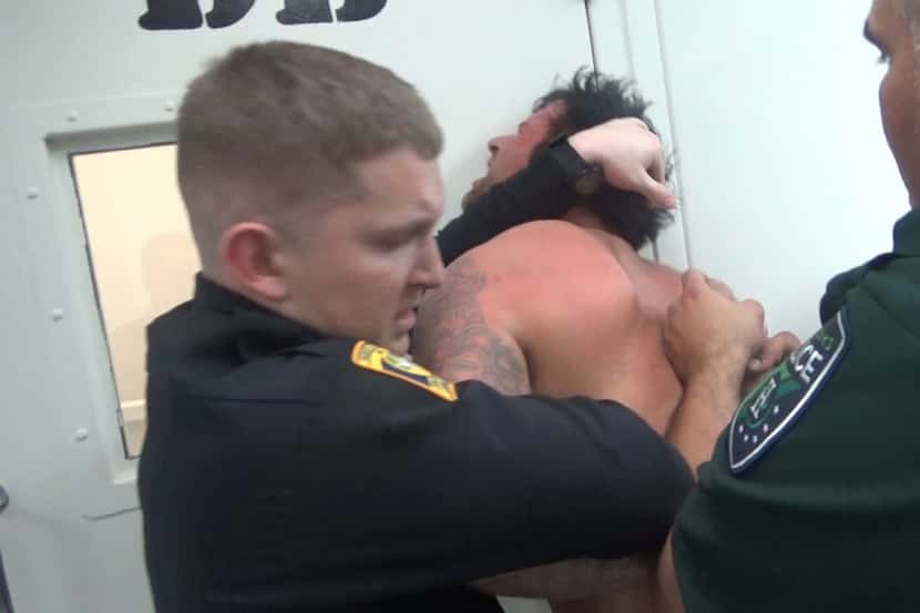 Jail staff and a local police officer restrain Andy DeBusk in 2016 while he was held inside...