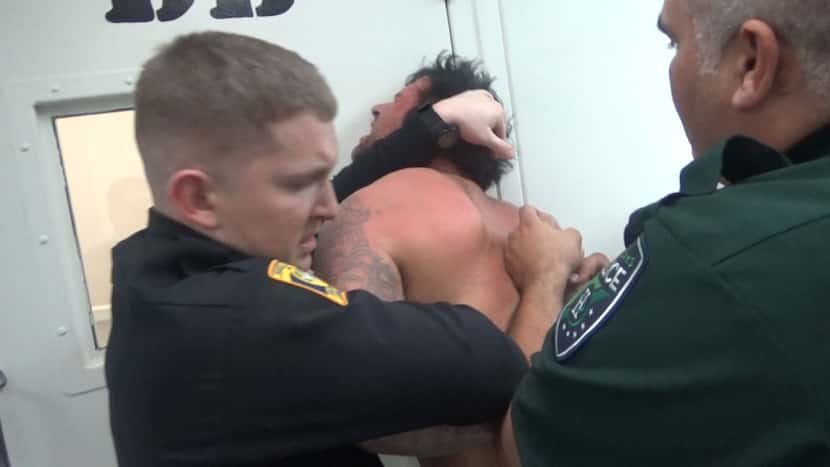 Jail staff and a local police officer restrain Andy DeBusk in 2016 while he was held inside...