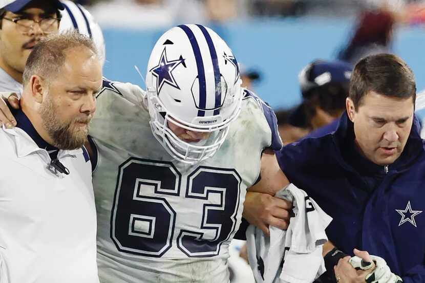 Dallas Cowboys center Tyler Biadasz (63) is helped to the locker room after hurting his...
