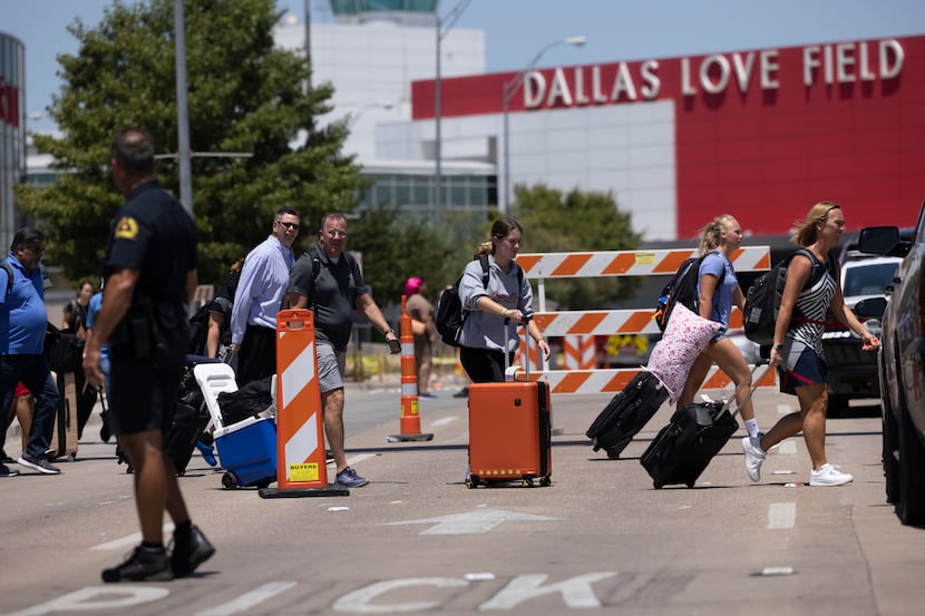 Travelers leave as Dallas police investigate reports of a shooting at Dallas Love Field...