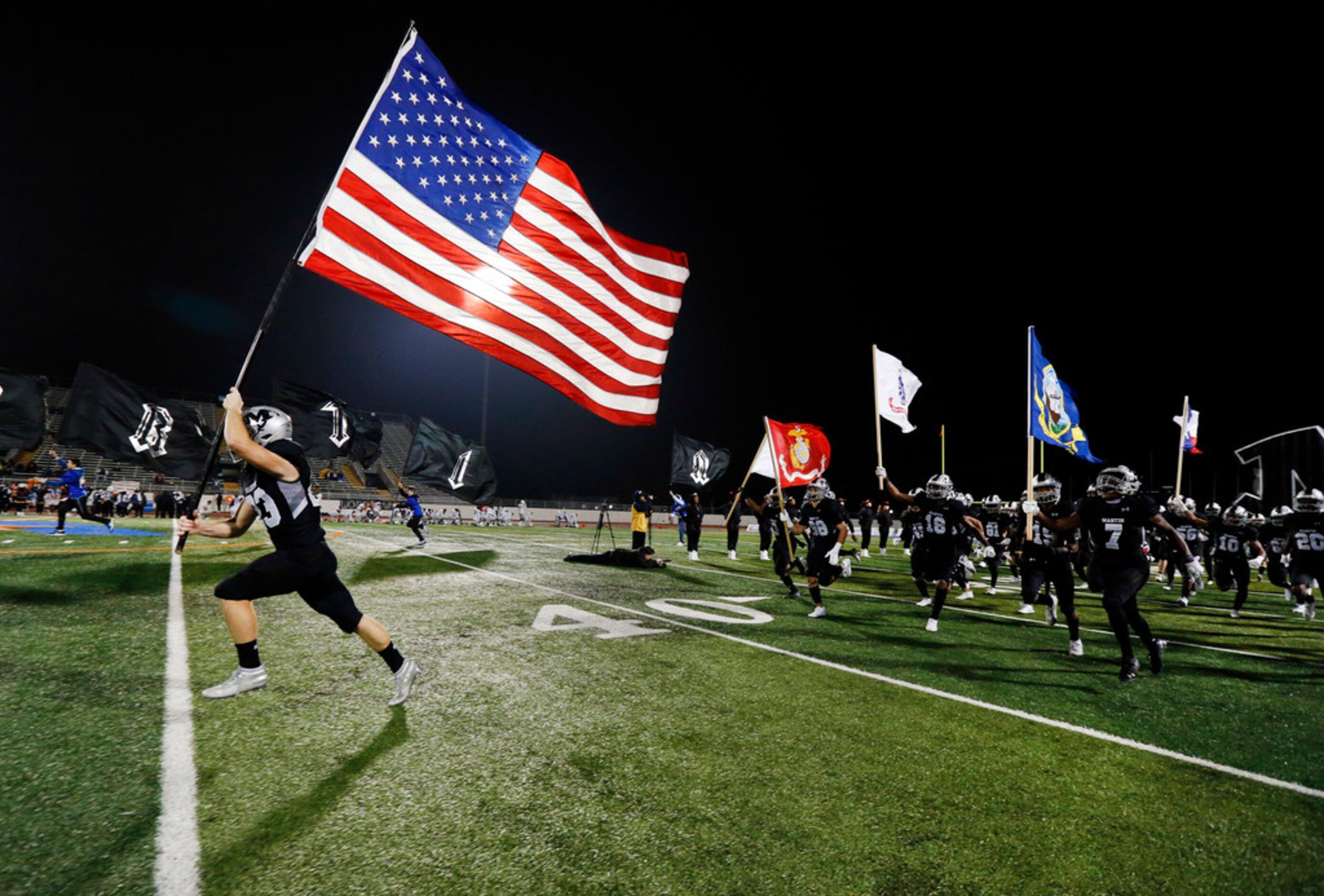 Martin High running back Jacob Colburn (23) carries the U.S. fly as his teammates carries...