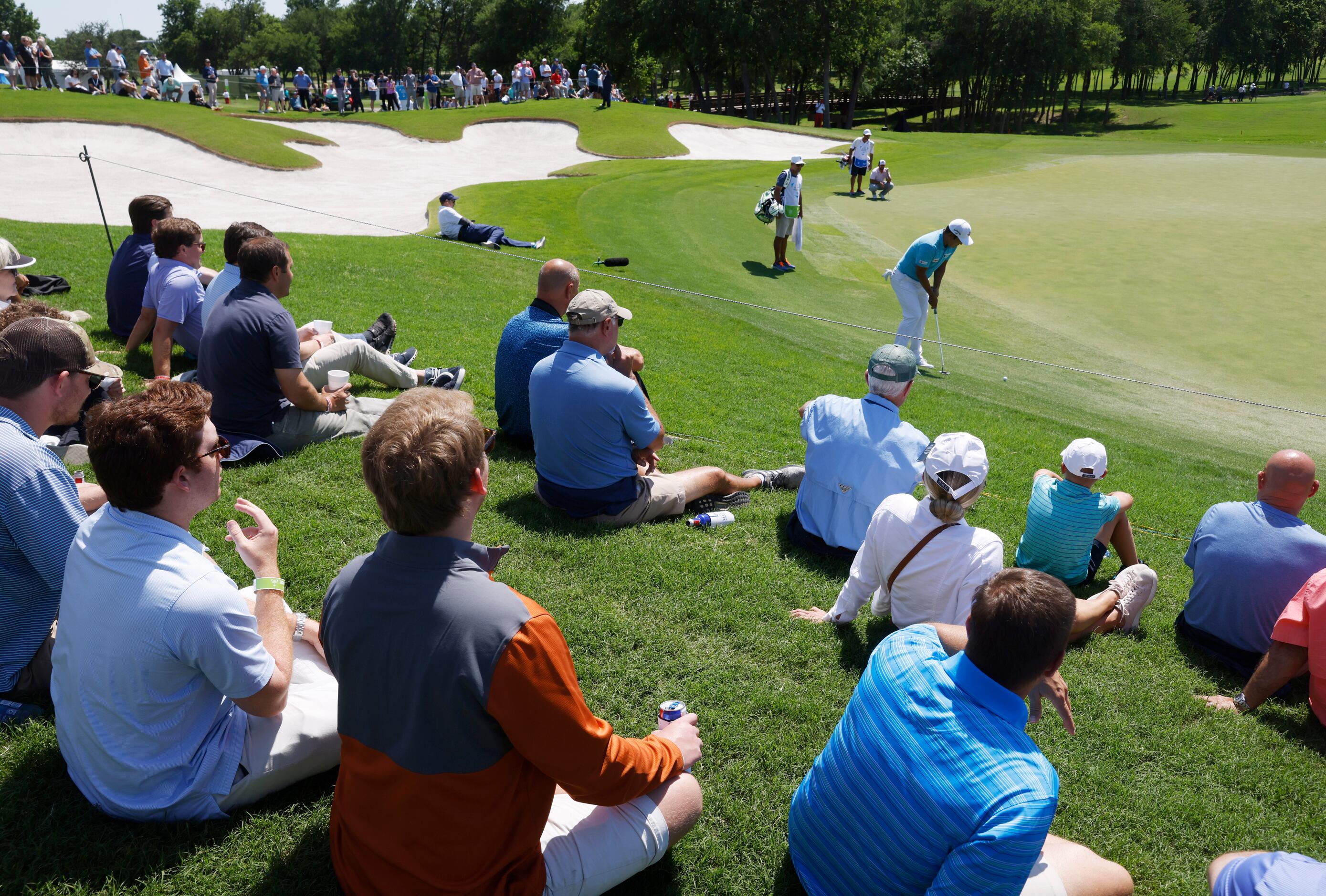 Fans watch as K.H. Lee hits a putt on the 12th hole during round 1 of the AT&T Byron Nelson ...