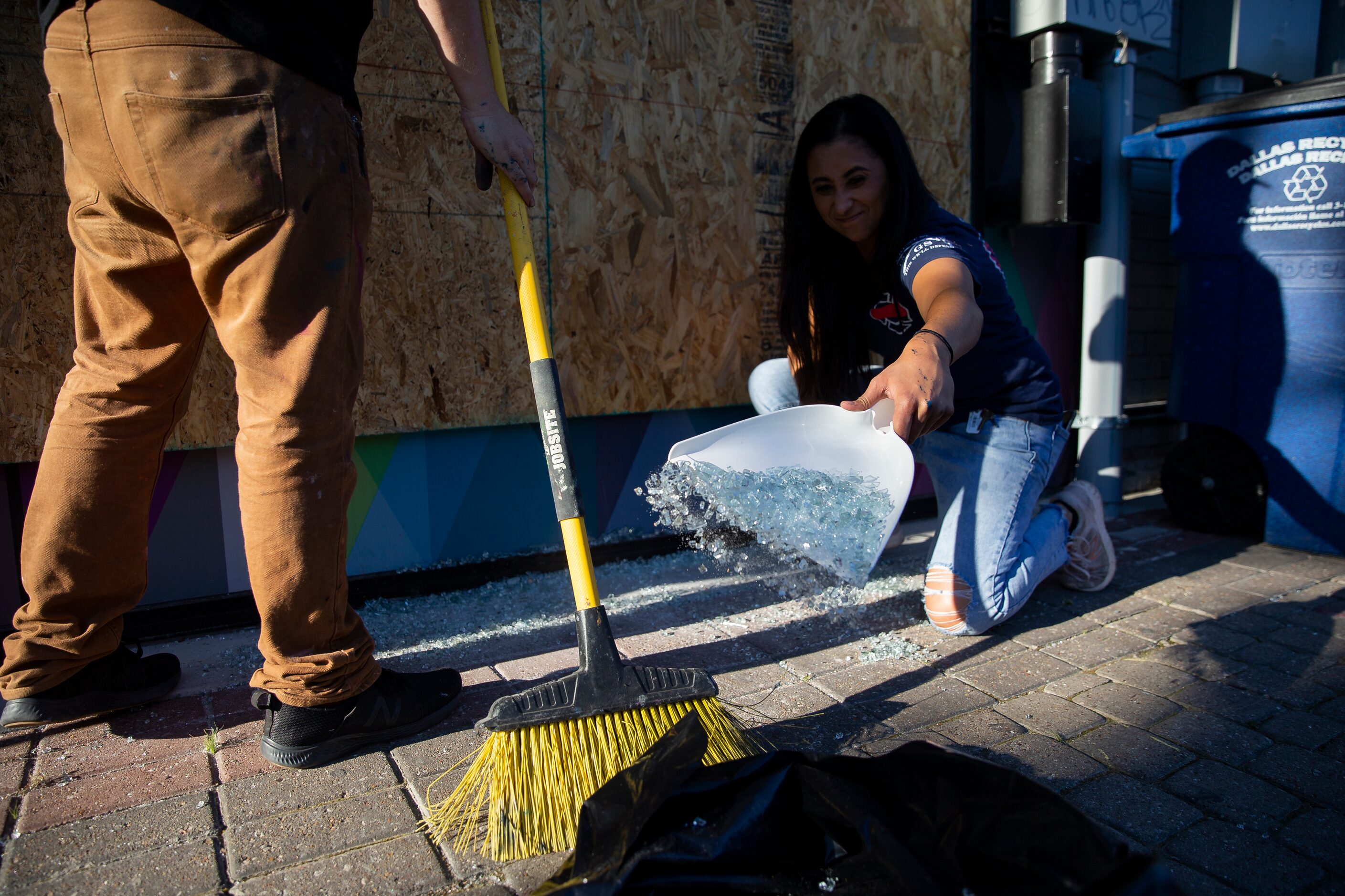 Reese Rodriguez helps clean glass from Upstairs Circus after being damaged during last...