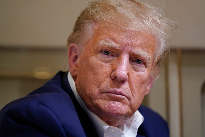 Former President Donald Trump listens as he speaks with reporters while in flight on his...