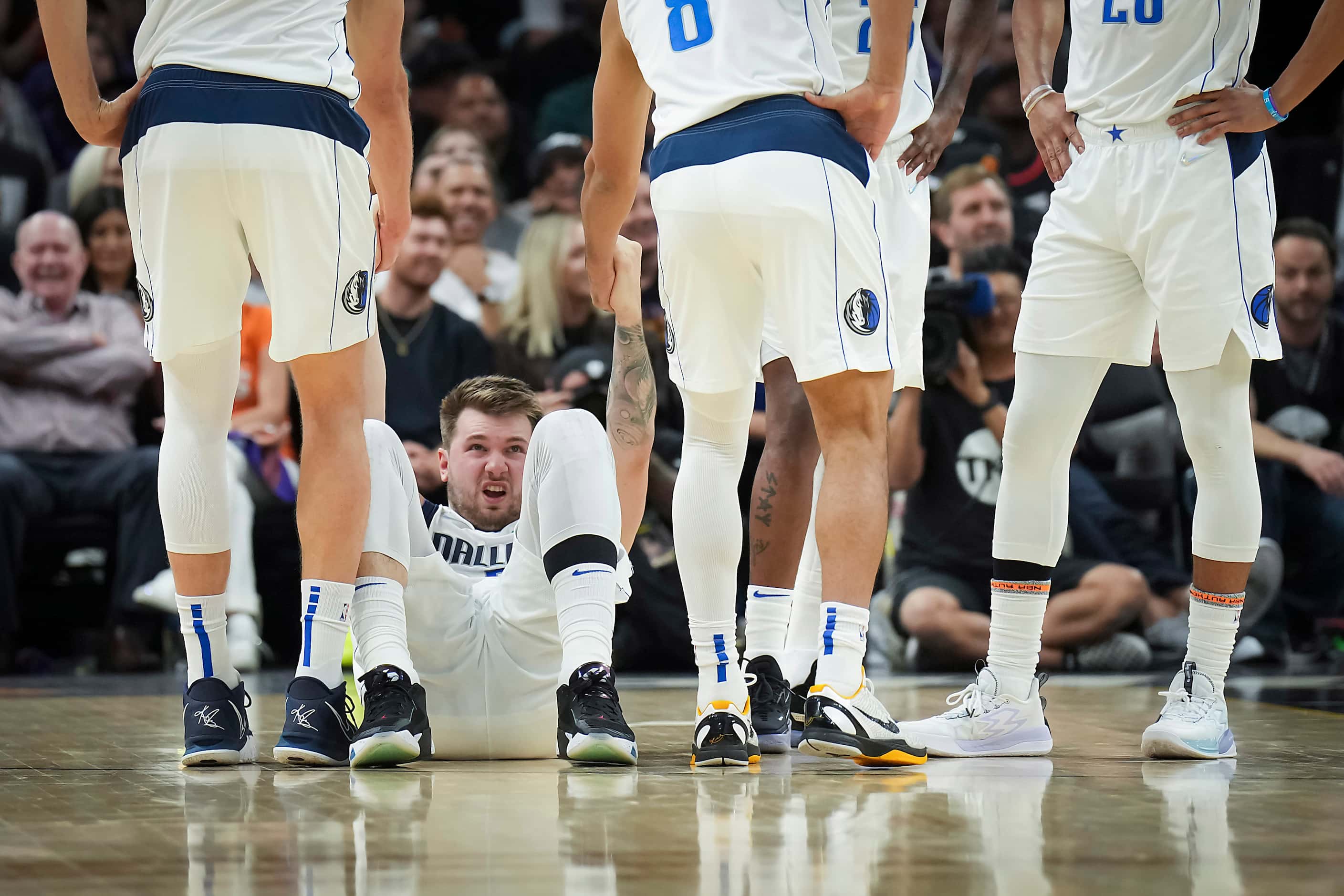 Dallas Mavericks guard Luka Doncic is helped up by teammates after being fouled by Phoenix...