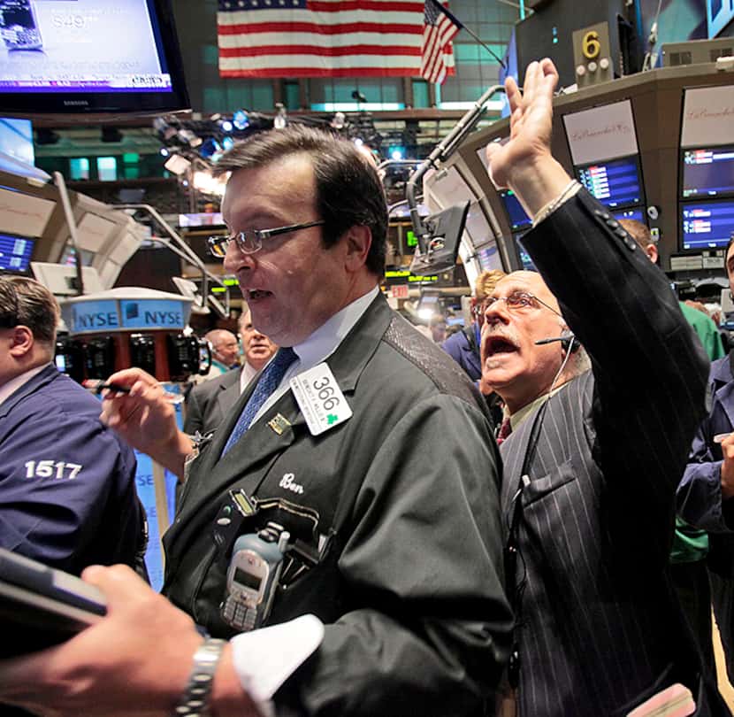  Traders Ben Willis, center, and Peter Tuchman work on the floor of the New York Stock...
