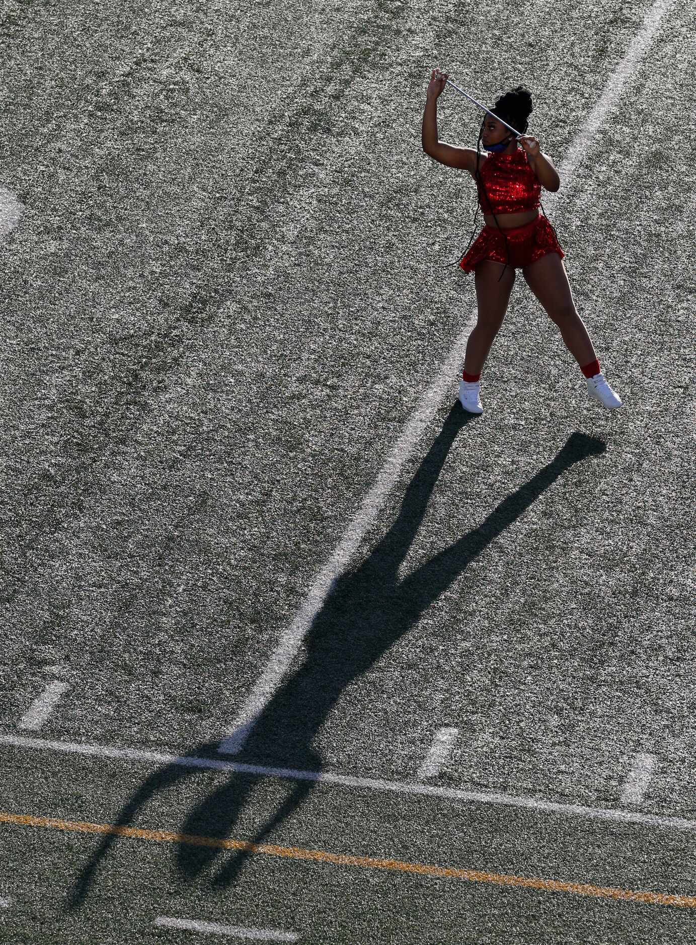 A Spruce majorette dances with her shadow before the start of the first half of the season...