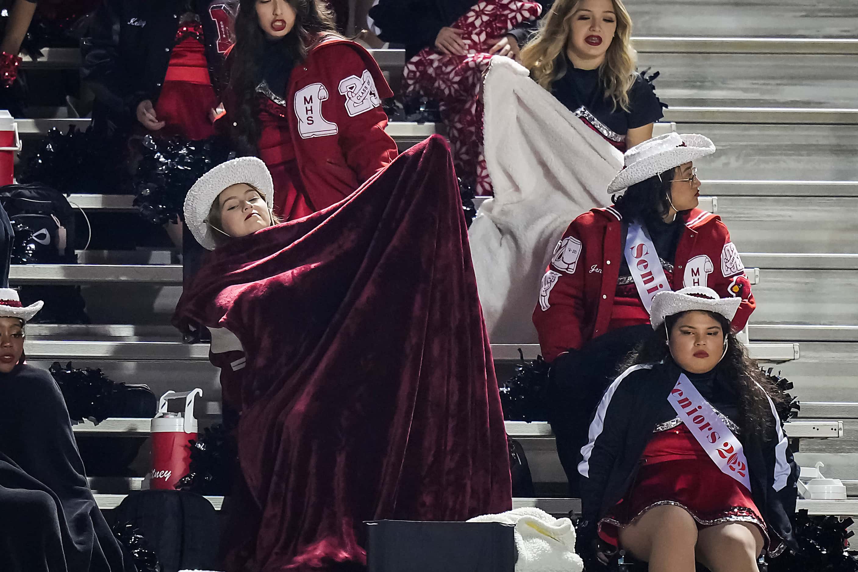 Irving MacArthur drill team members bundle up under blankets during the first half of a...