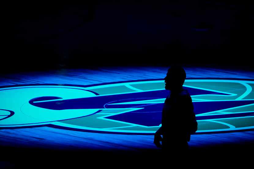 A player is silhouetted against the Dallas Mavericks logo before an NBA basketball game at...