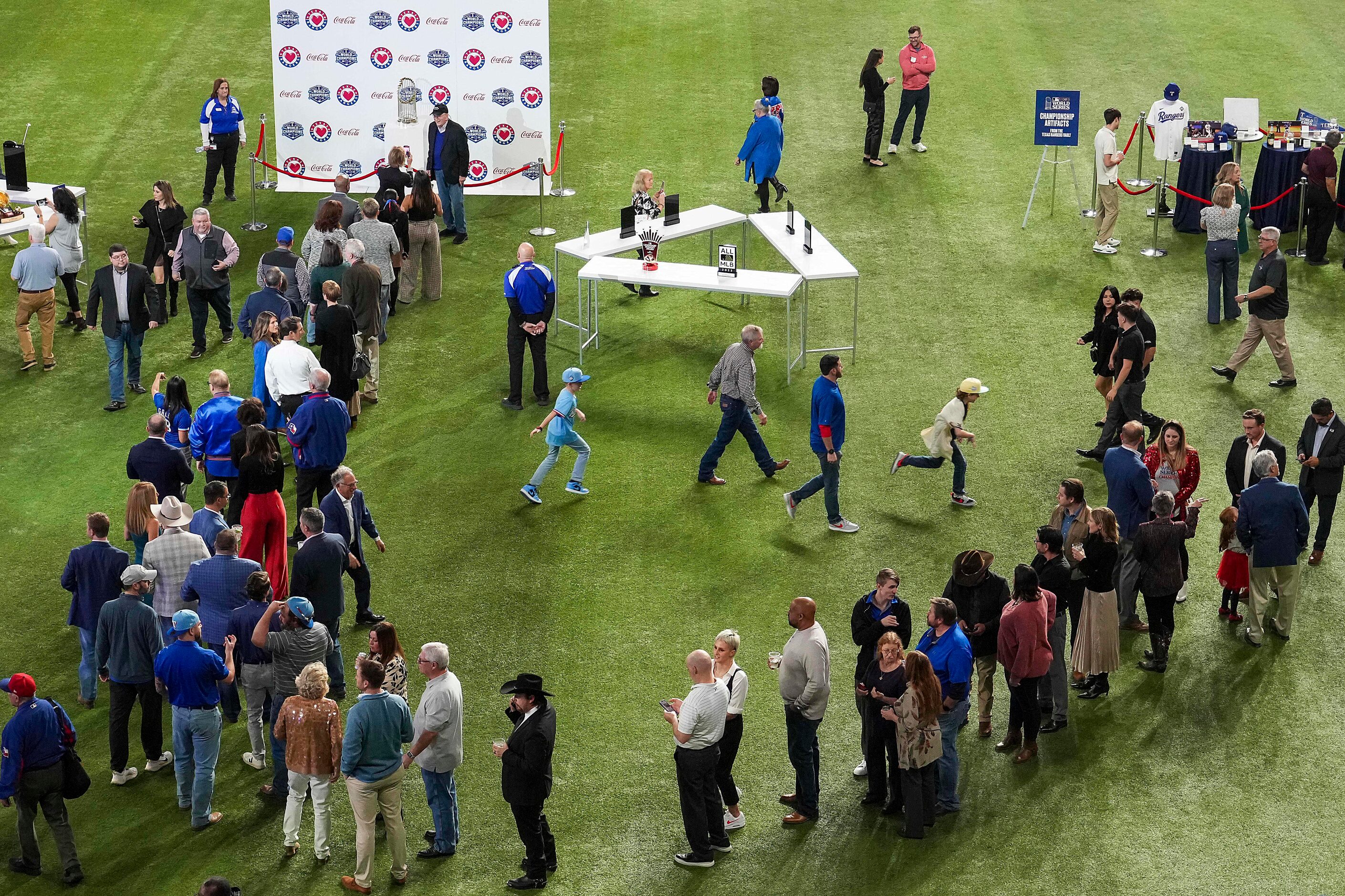 Guests wait in line to take a photo with the Commissioner’s Trophy during the Texas Rangers...