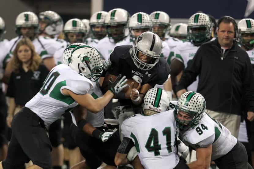 Arlington Martin QB Eric Hughes (2) is swarmed by the Southlake Carroll defense in the first...