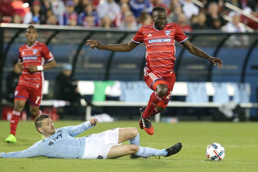 FC Dallas forward Roland Lamah, right, jumps over the tackle against Sporting Kansas City...