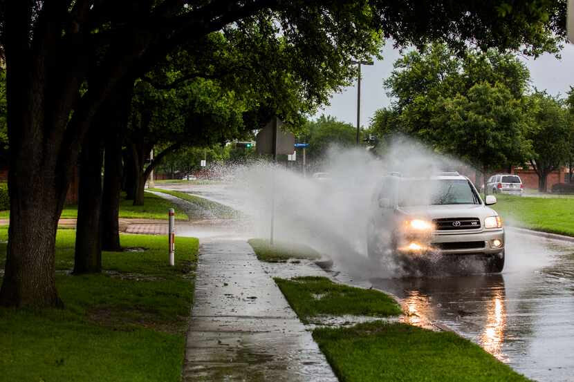 A vehicle splashes through rain water puddles on North MacArthur Boulevard as storms rolled...