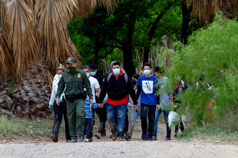 A U.S. Customs and Border Patrol agent leads a group of migrants, mostly from Venezuela, out...