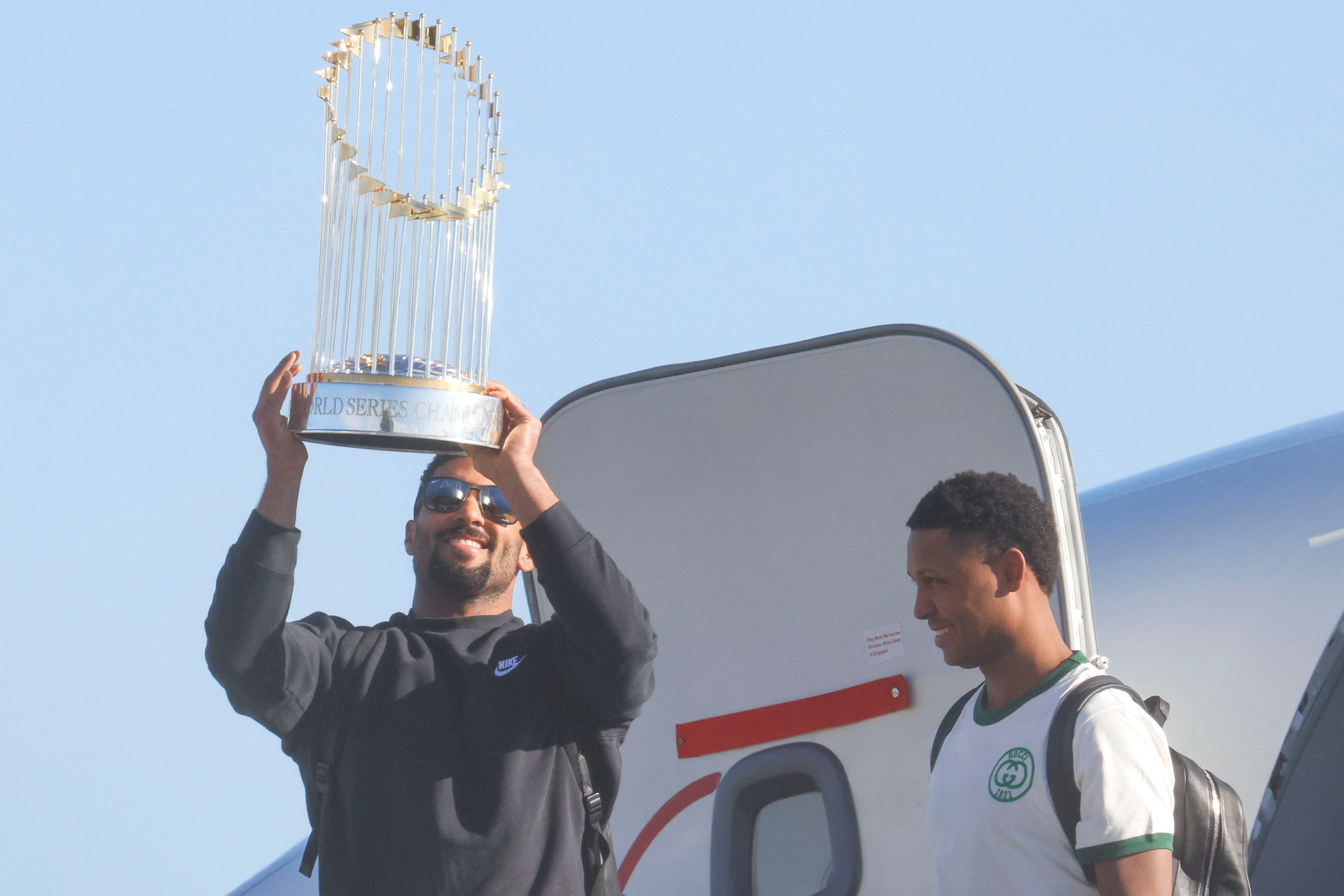 Texas Rangers’ Marcus Semien hoists the Commissioner's Trophy by pitcher José Leclerc upon...