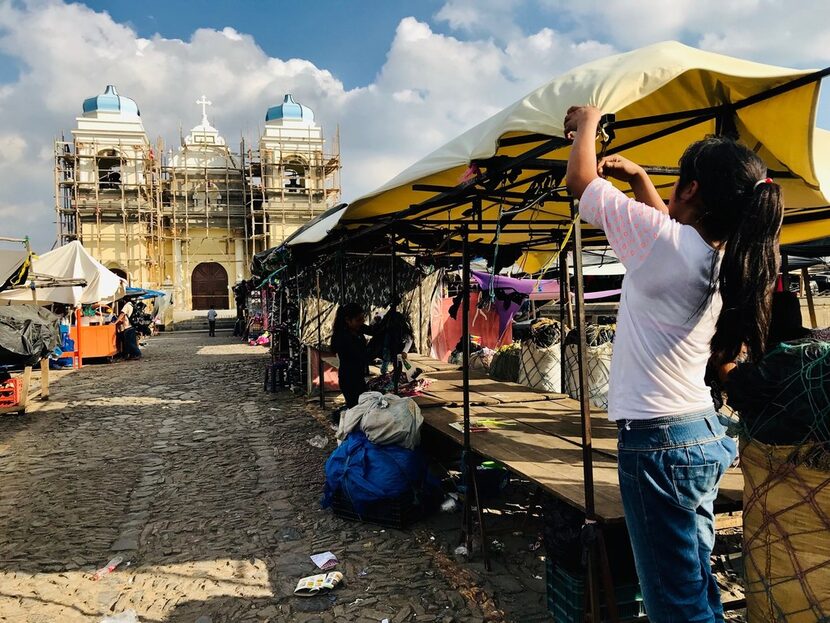 Workers at the open-air market in San Martin Jilotepeque pack up to leave. The church is...