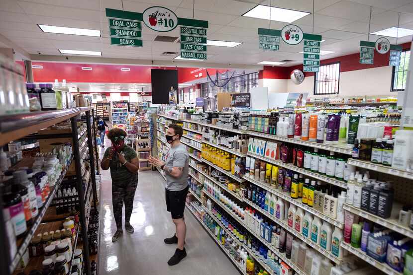 Vitamin Clerk Joel Hartom, right, helps customer Tina Watts look for an aroma product inside...