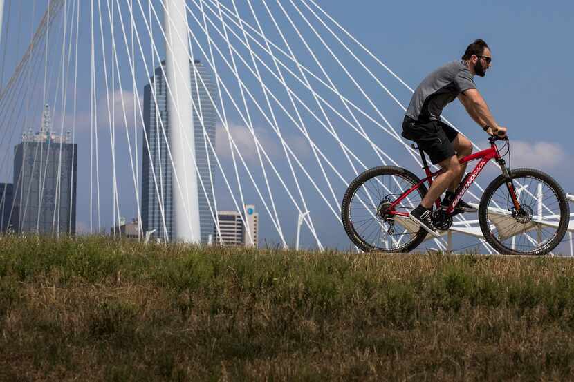 A cyclist passes the Margaret Hunt Hill Bridge while riding on the Trinity Skyline Trail in...