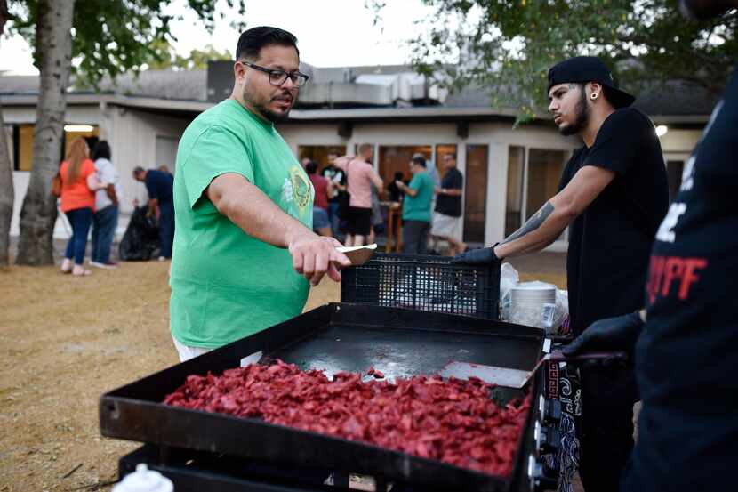 Trompo owner Luis Olvera, left, speaks with cooks about preparing pork for his Trompo Burger...