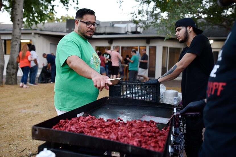 Trompo owner Luis Olvera, left, speaks with cooks about preparing pork for his Trompo Burger...