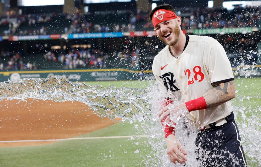 After avoiding the ice water bucket, Texas Rangers catcher Jonah Heim (28) received the...