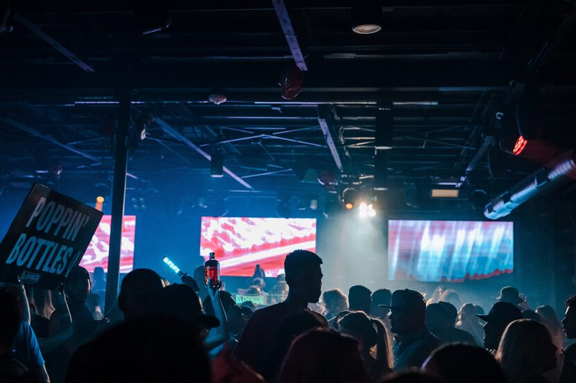 Foto de un club con gente bailando bajo luces azules.