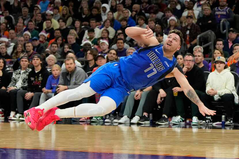 El jugador de los Mavericks de Dallas, Luka Doncic, cae a la duela en el juego ante los Suns...