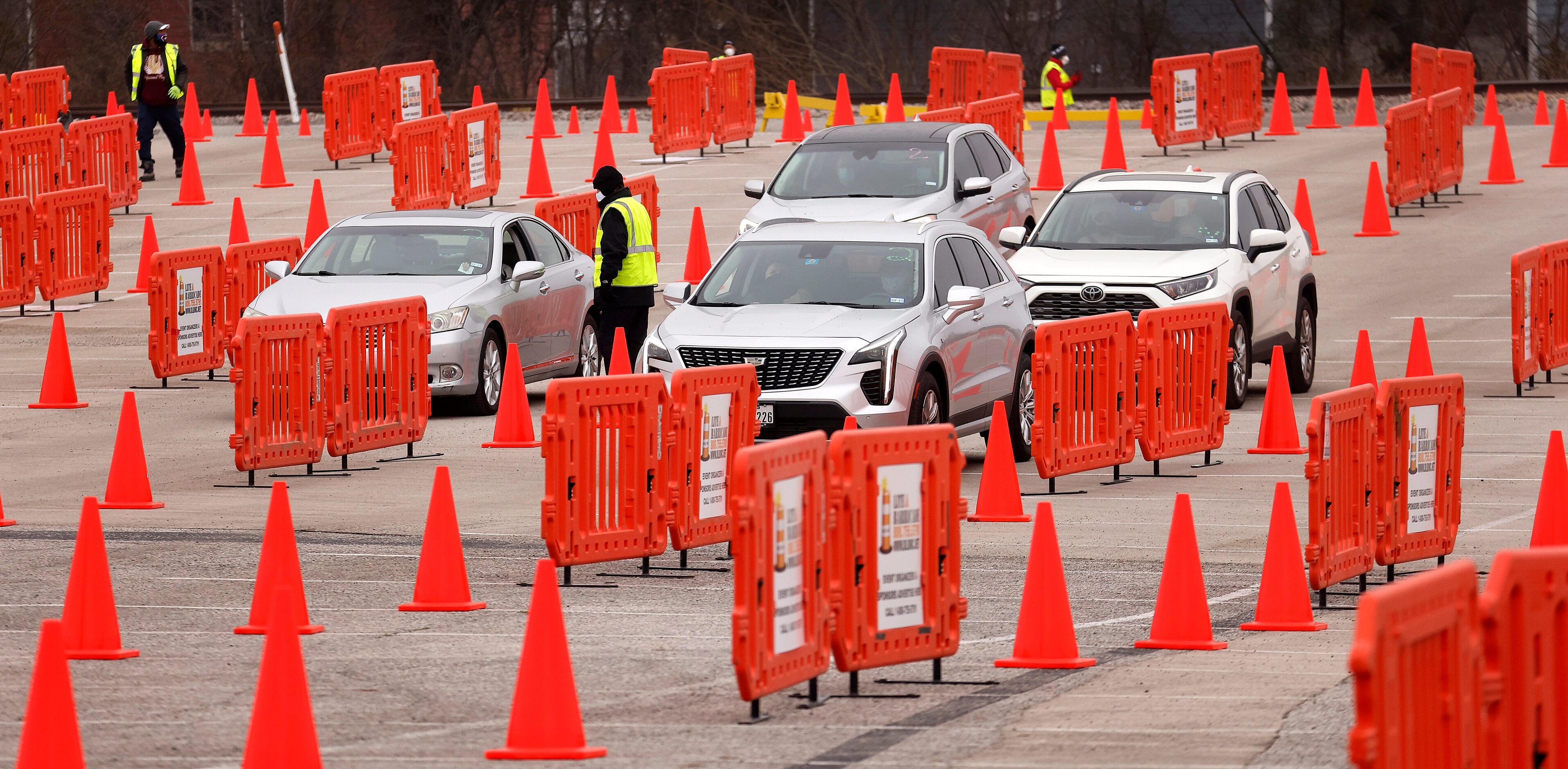 A volunteer helps people navigate the drive-thru lanes before receiving their COVID-19...