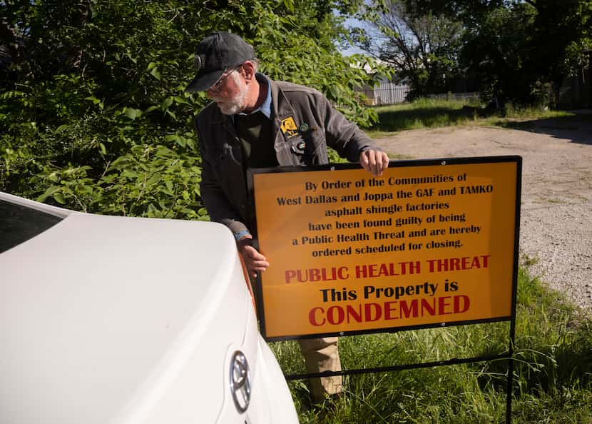 Jim Schermbeck with Downwinders at Risk loads a sign back into his car after blocking the...