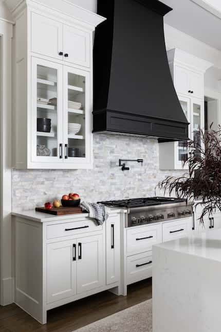 White kitchen with black vent hood and fruit on the countertop