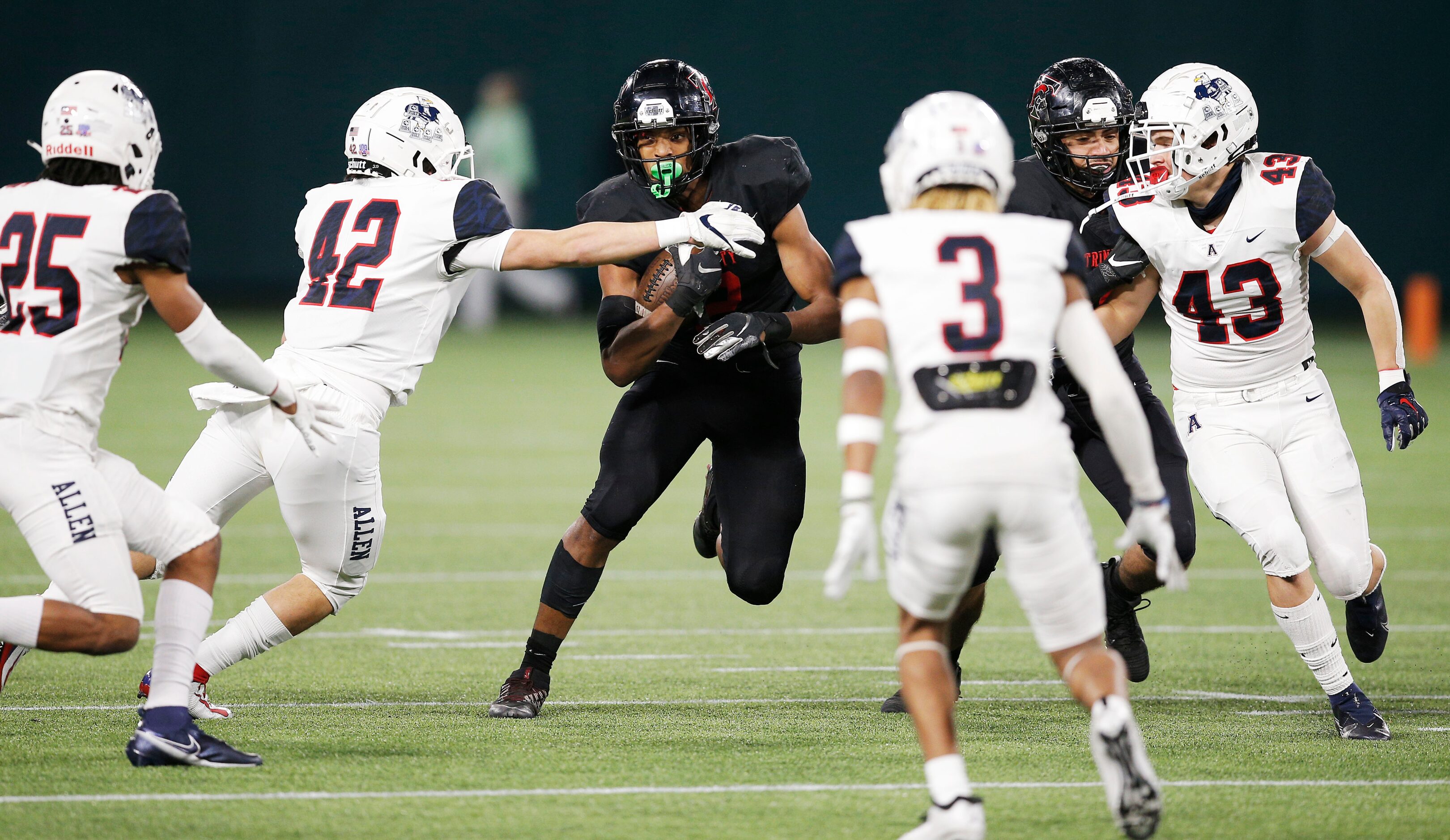 Euless Trinity junior running back Ollie Gordon, center, looks for room against the Allen...