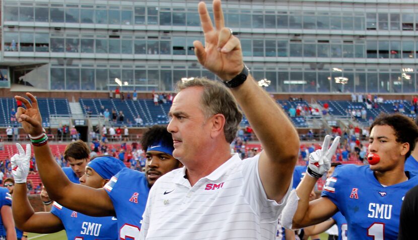 SMU head coach Sonny Dykes pauses with his players for the playing of their school song...