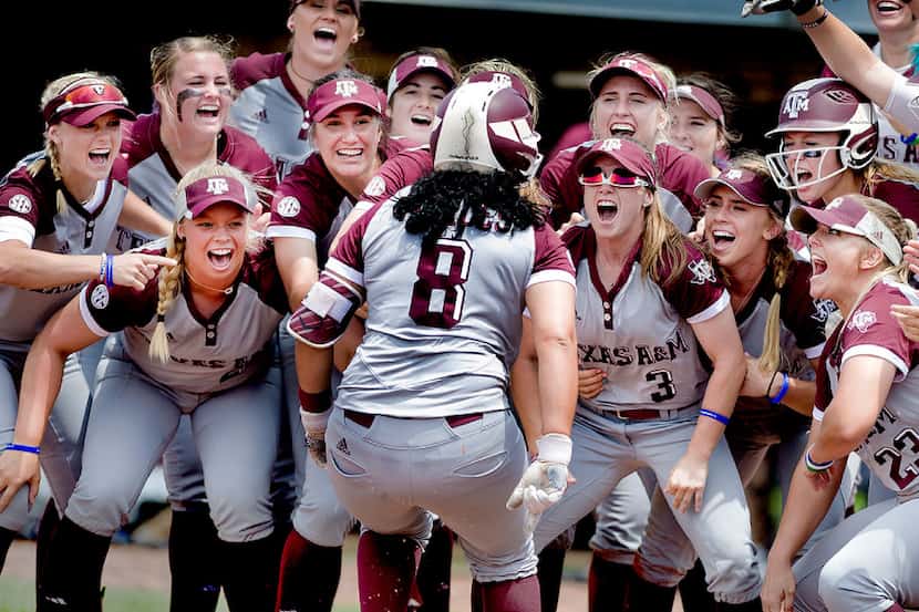 The Texas A&M softball team cheers welcomes Tori Vidales (8) as she touches home plate after...