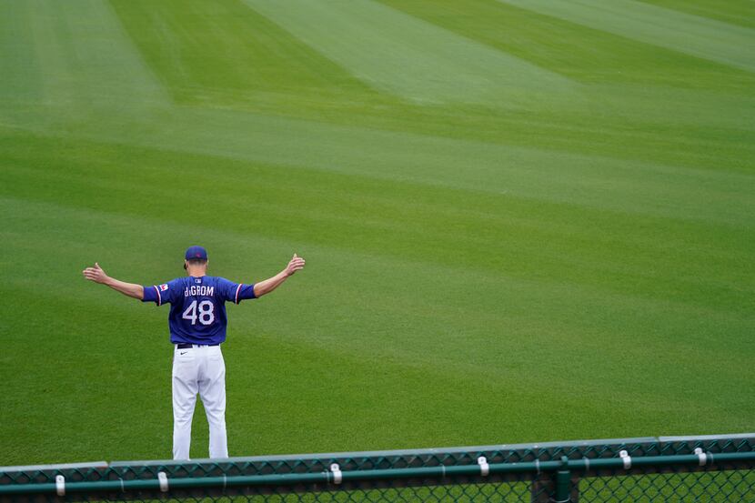 Texas Rangers starting pitcher Jacob deGrom warms up for the team's spring training baseball...