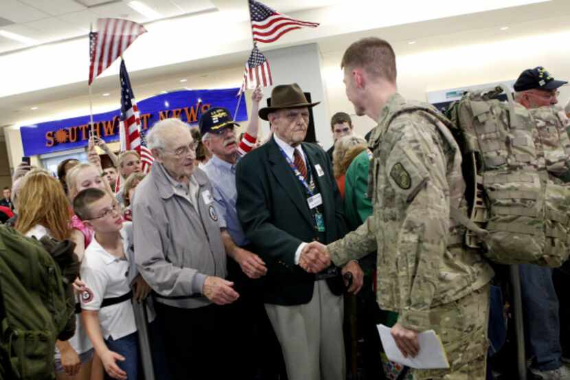Family, friends, and volunteers (no names available) greet troops on March 14, 2012, on the...