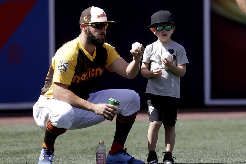 National League's Jake Arrieta, of the Chicago Cubs, kneels with his son, Cooper Arrieta,...
