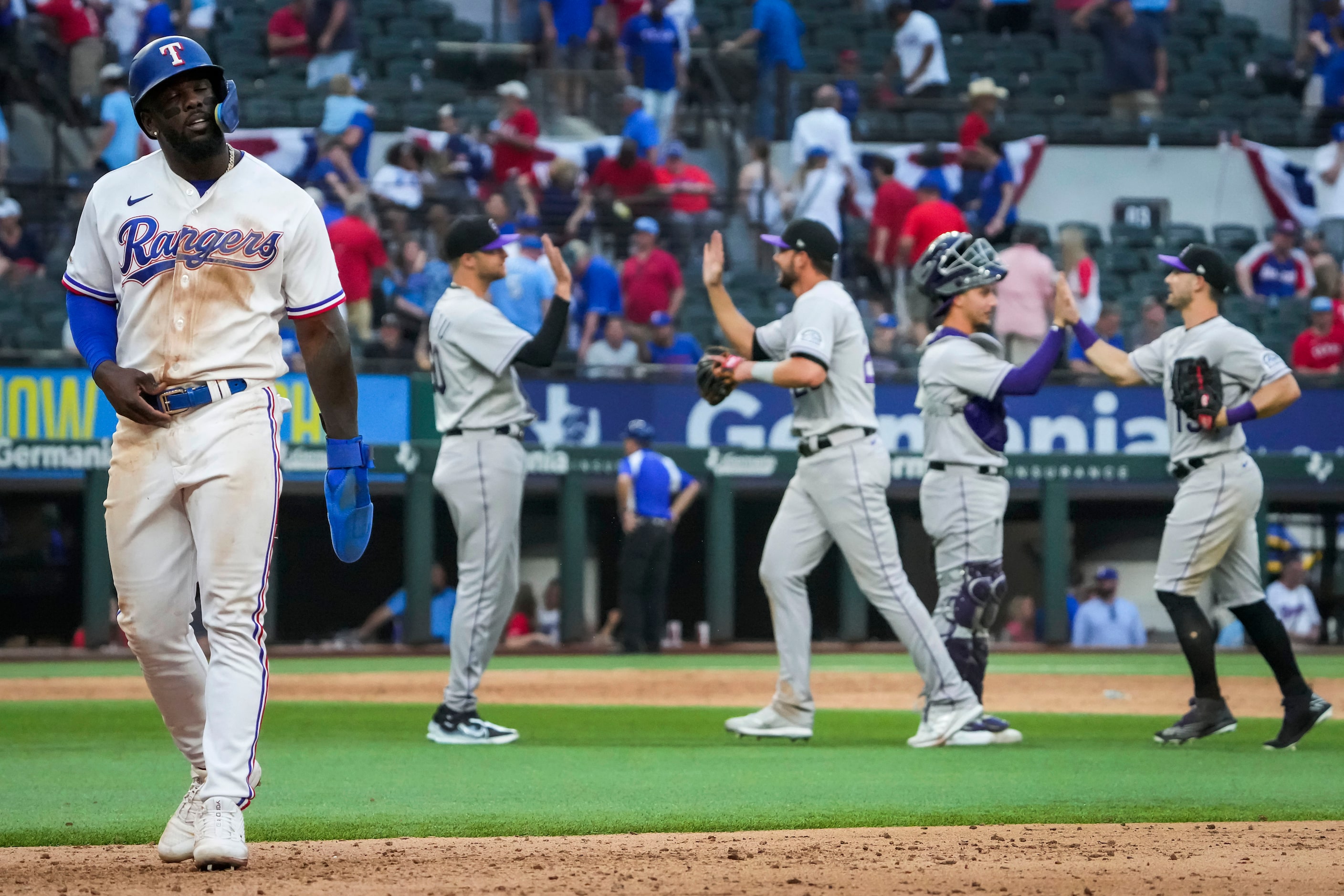 Texas Rangers center fielder Adolis Garcia walks off the field as Colorado Rockies players...