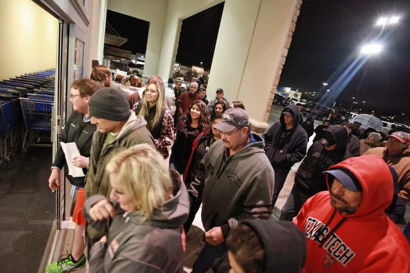 Shoppers rush through the entrance to the Academy Sports+Outdoors at 5:00 a.m. in the...