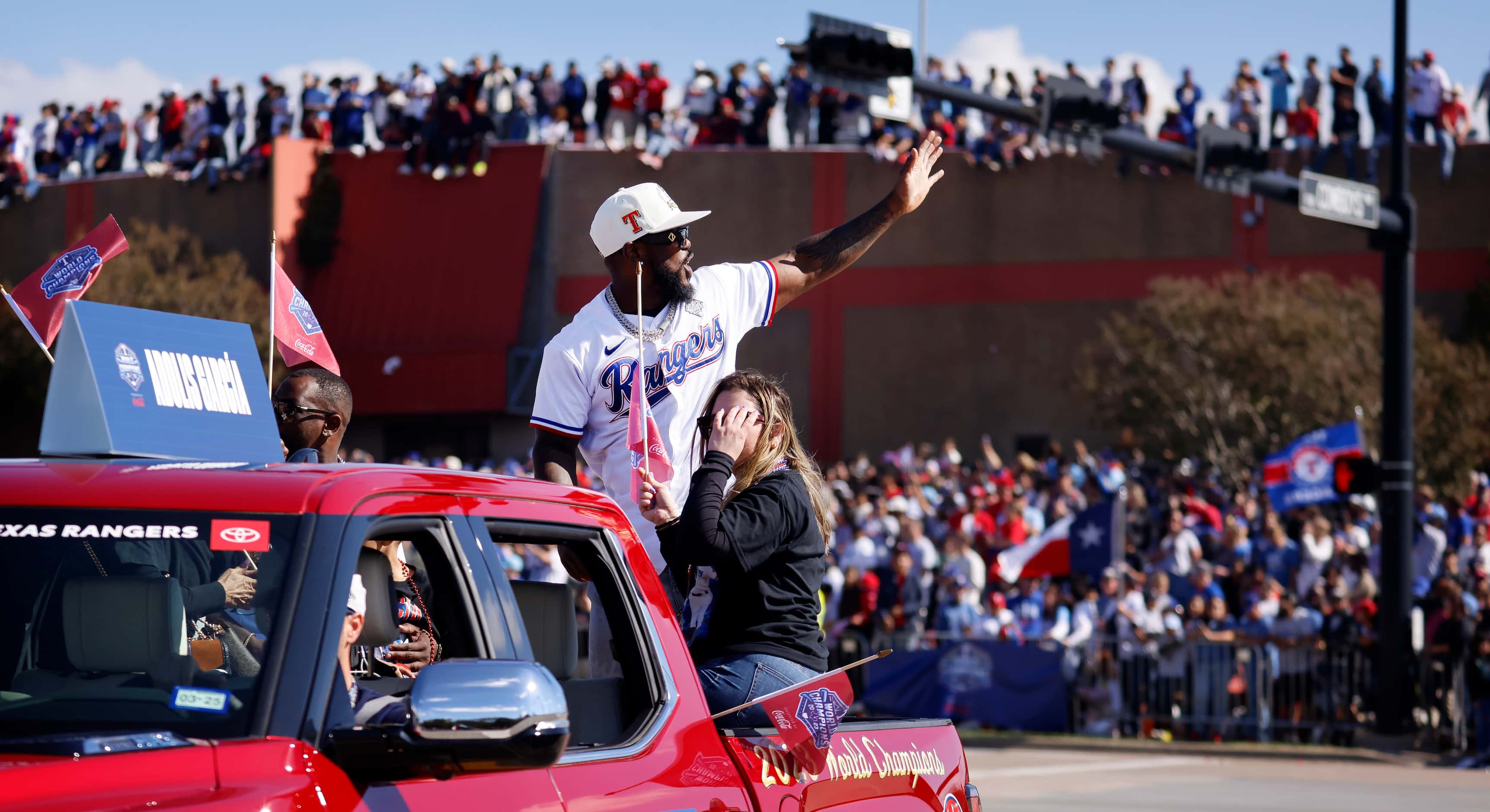 Texas Rangers right fielder Adolis Garcia waves to fans lining the streets and buildings...