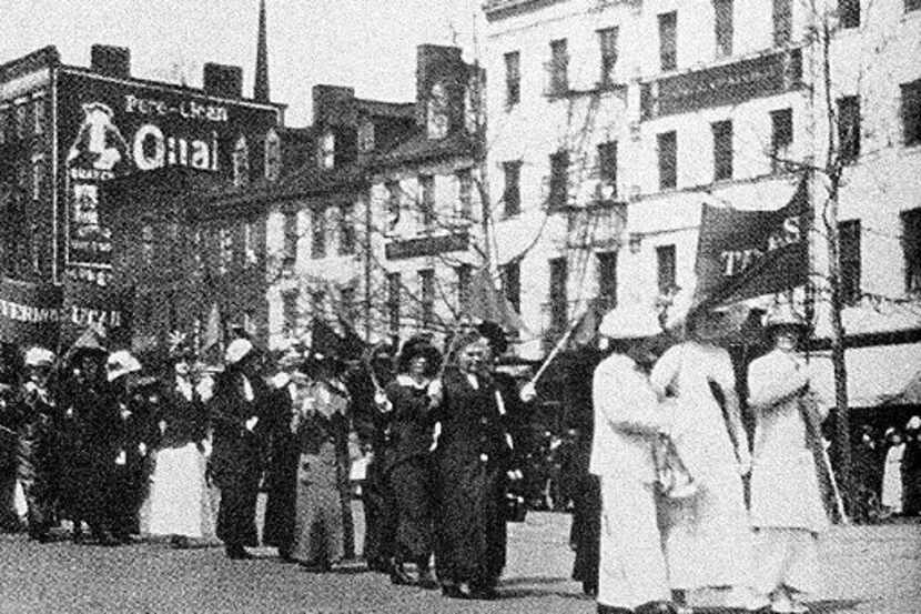 A group of Texas Women, led by three dressed in white, marched in a suffrage parade under...