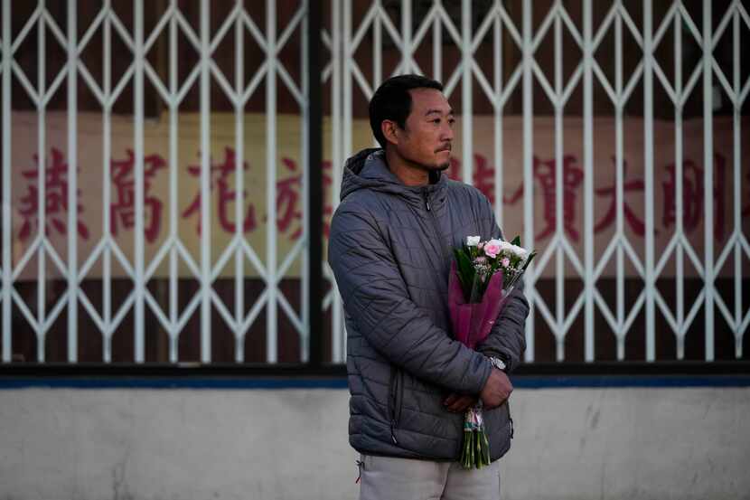 Hunter Zhao, de 41 años, porta flores para honrar a las víctimas del atentado del sábado en...