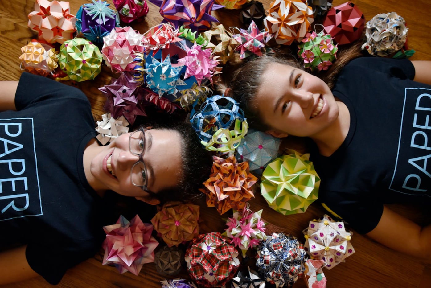 Katherine Adams, 12, (left) and her sister Isabelle Adams, 14, with origami ornaments made...