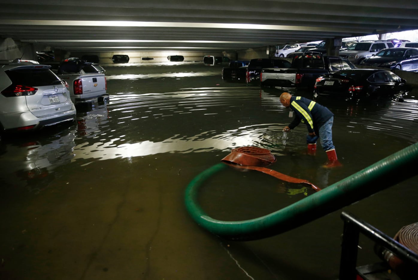 City of Dallas employee Holvin Rivera Reyes removes debris as water is pumped out of the...