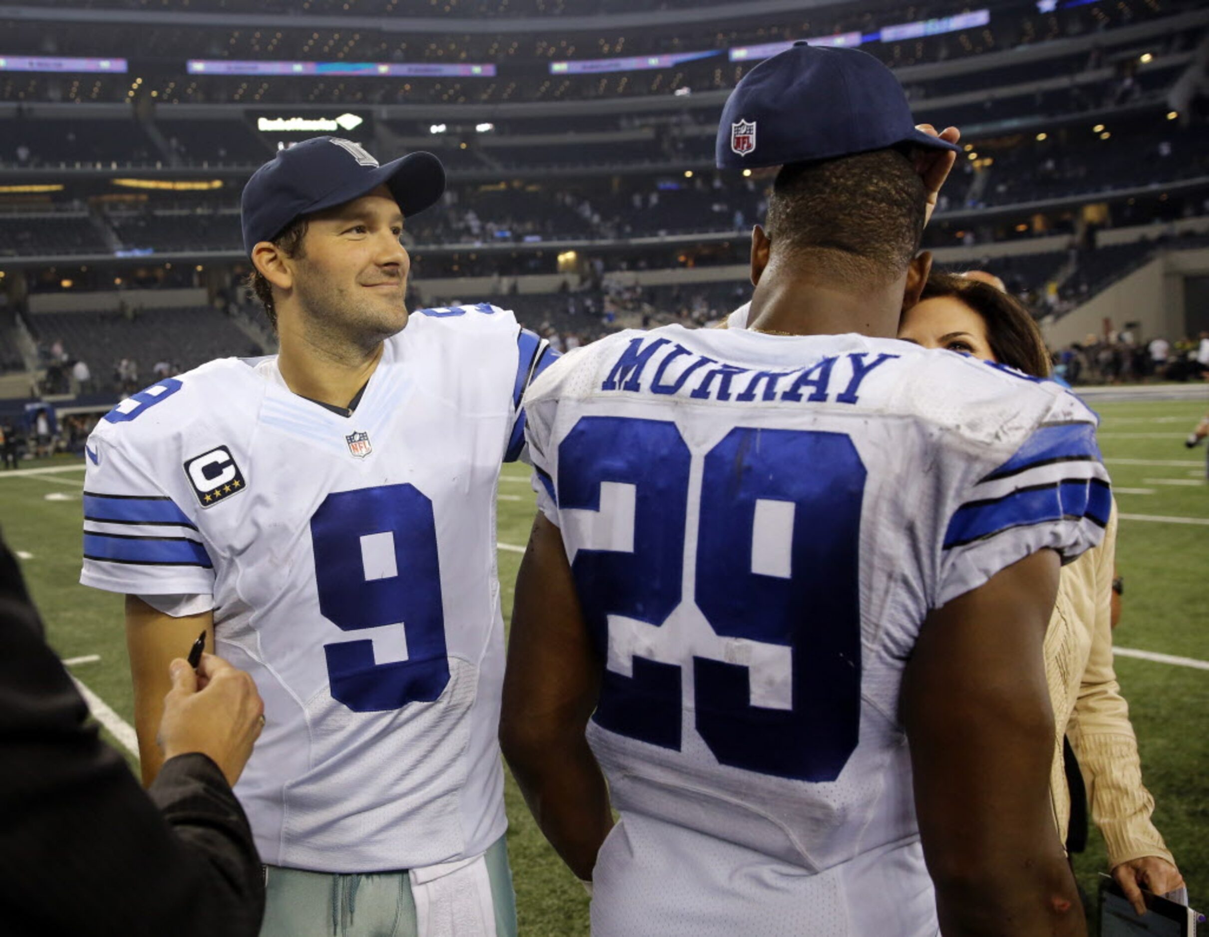 Dallas Cowboys quarterback Tony Romo (9) turns running back DeMarco Murray's (29) hat around...